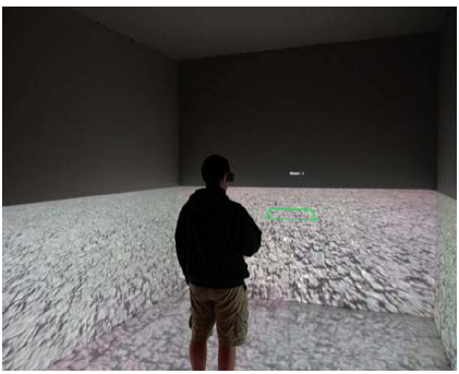 Fig. 2. A participant stands in the C6 viewing the virtual environment used in Experiment 1. The virtual green rectangle in front of the participant is one of the stimuli used to evaluate perceived depth and width.